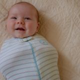 Smiling baby wearing DIY swaddle