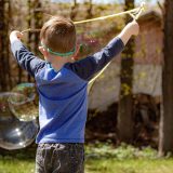 Young boy with tri-string bubble wand and two giant bubbles